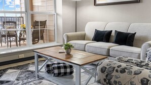 A living room with a sofa, a coffee table, and a view of the outdoors. - Waters Edge Retreat - For 6! (Branson)