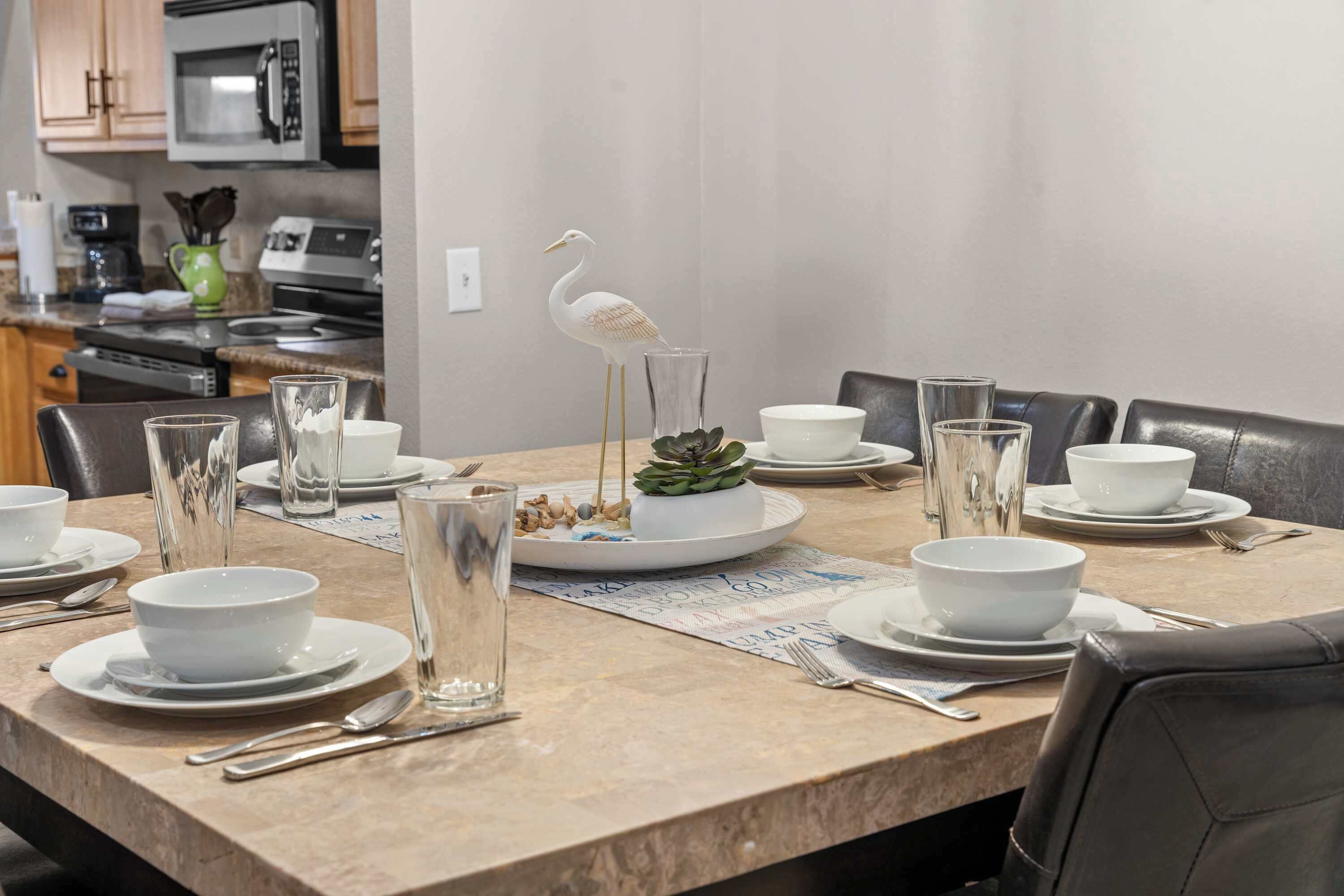 A dining table set with white bowls, glasses, and cutlery, a decorative bird sculpture, and a succulent plant.