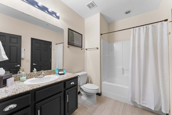 A bathroom with a sink, toilet, and shower area. - Waters Edge Retreat - For 6! (Branson)