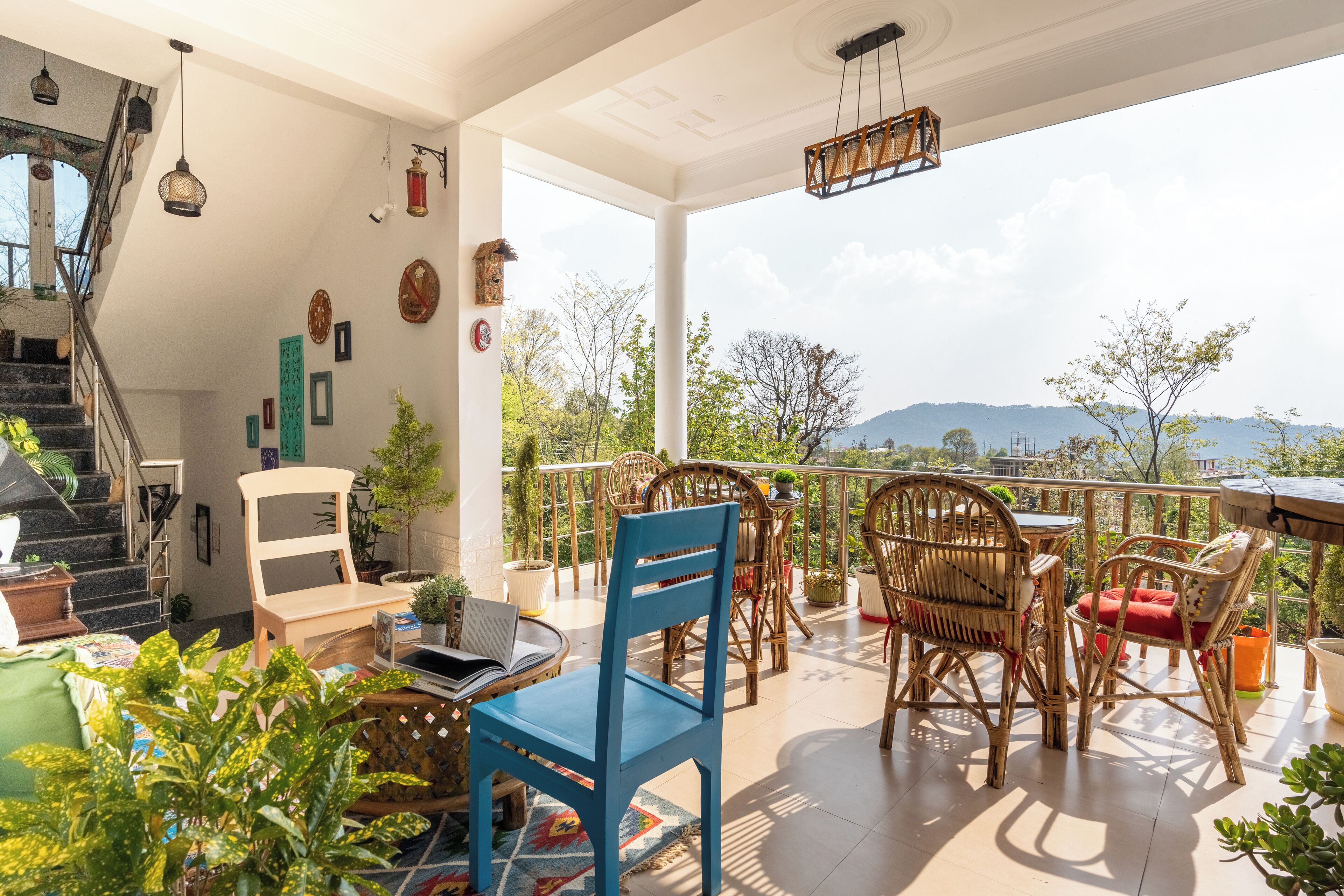 A spacious balcony with wicker furniture, potted plants, and a view of distant mountains.