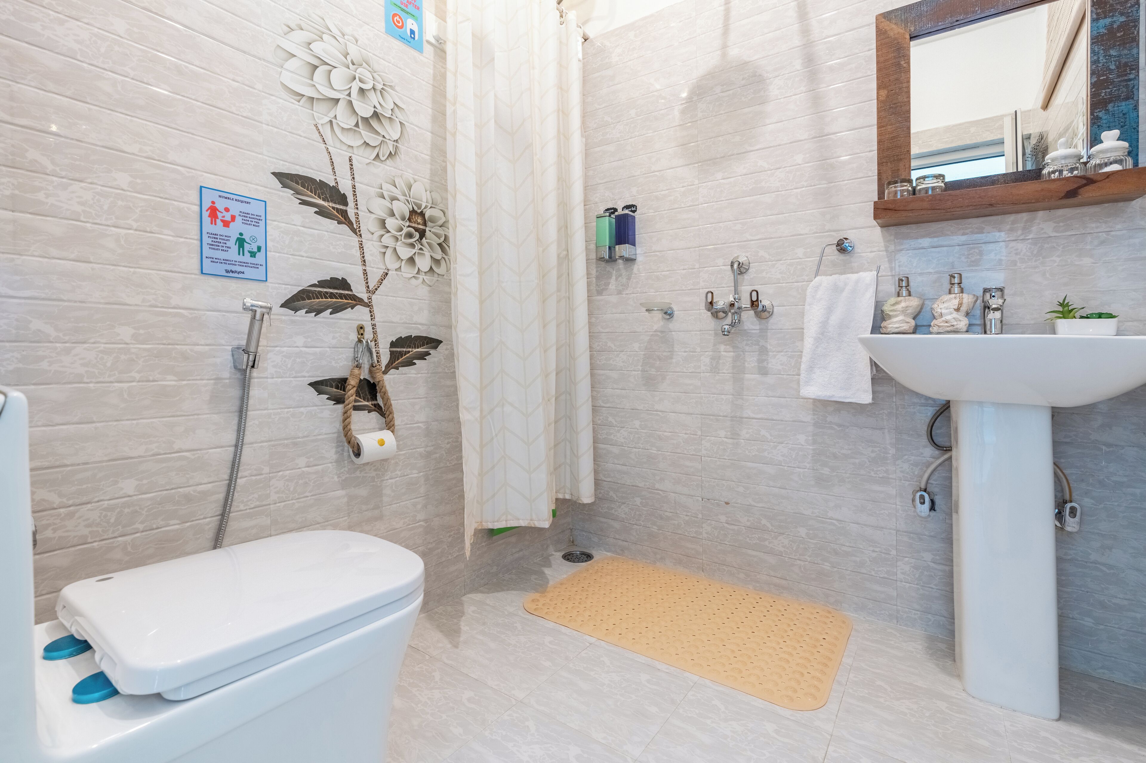A bathroom with a toilet, shower, sink, and decorative elements like a flower wall and a mirror.