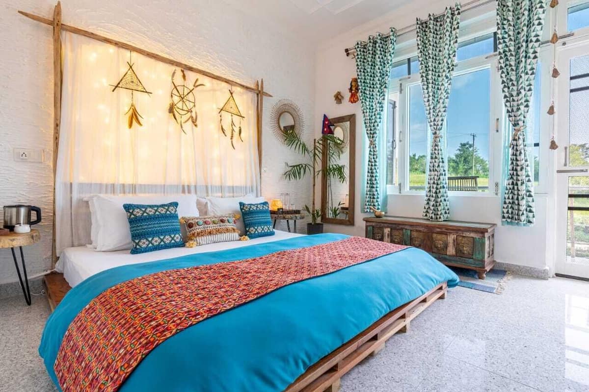 Ein geräumiges Schlafzimmer mit einem großen Bett, einem hölzernen Kopfteil und Blick ins Freie durch große Fenster.