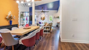 A dining area with a wooden table, red and grey chairs, a chandelier, and a ceiling fan.