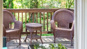 A wooden deck with wicker furniture, including two chairs and a small table.