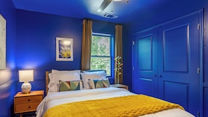 A bedroom with a bed, a nightstand, a window with curtains, and a door.