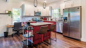 A modern kitchen with a central island, stainless steel appliances, and a seating area with bar stools.