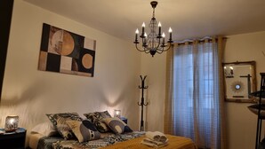 A bedroom with a bed, a chandelier, a painting, and a mirror.