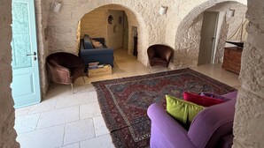 Une pièce rustique aux murs de pierre, avec un plafond haut, un canapé bleu, un canapé violet et un tapis à motifs.