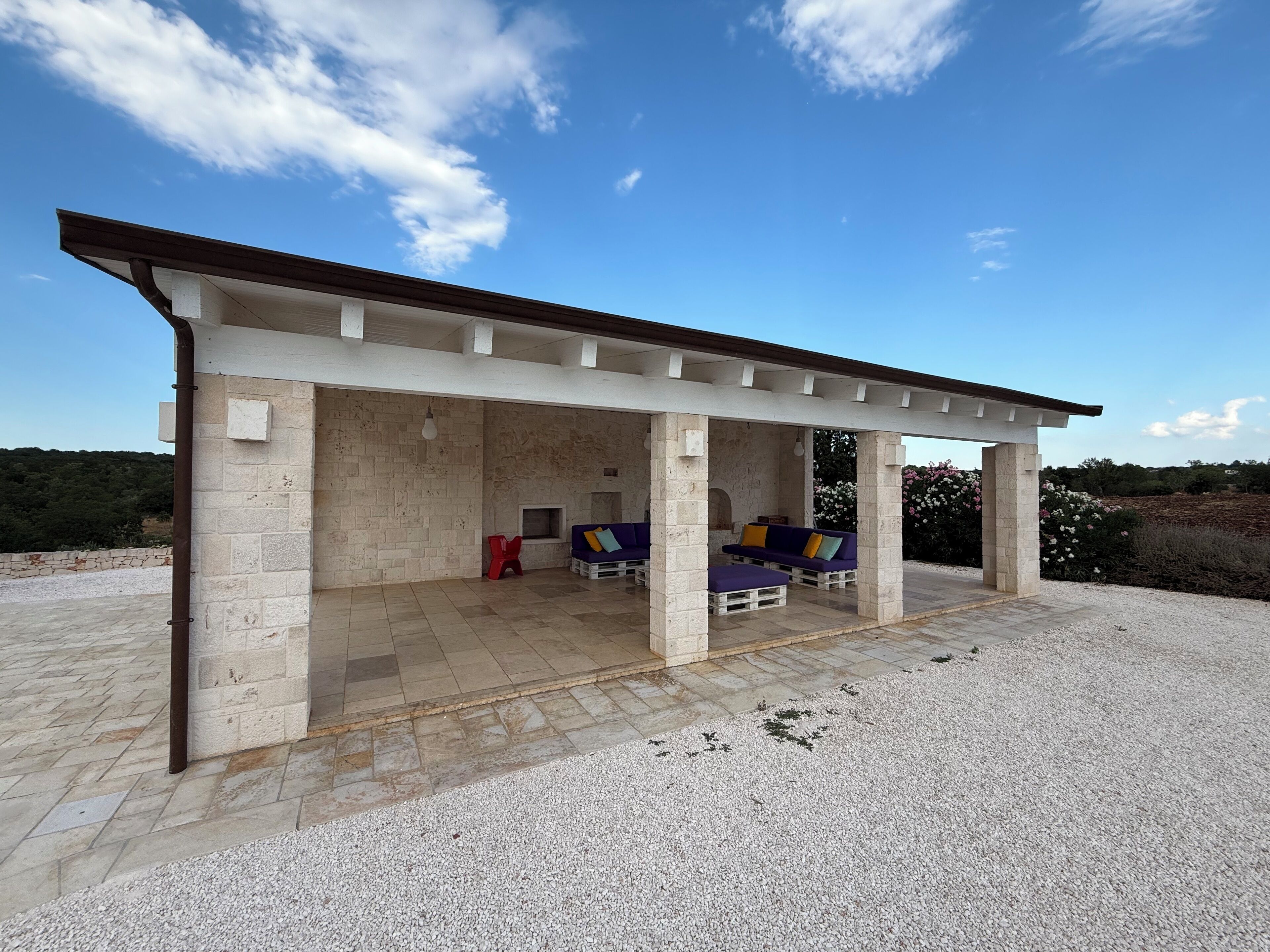 A covered outdoor seating area with stone walls and a gravel floor.