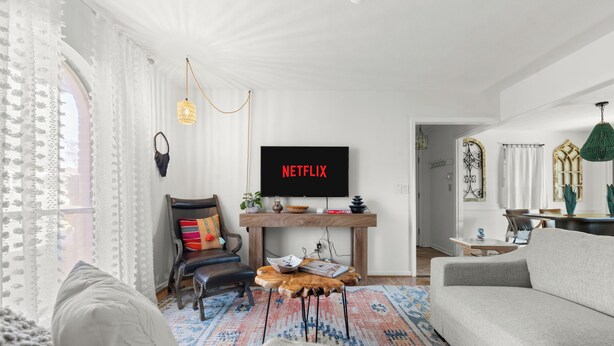 A modern living room with a sofa, a coffee table, and a TV displaying 'NETFLIX'. - Abuela House with Pool - 4Bed (Columbus)