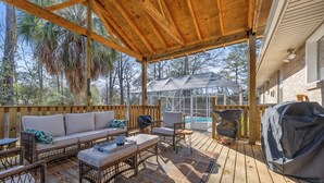 A covered outdoor deck with a sofa, chairs, a grill, and a pool. - Abuela House with Pool - 4Bed (Columbus)