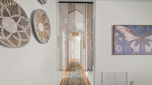 A hallway with a patterned rug, a decorative wall hanging, and a butterfly artwork. - Abuela House with Pool - 4Bed (Columbus)