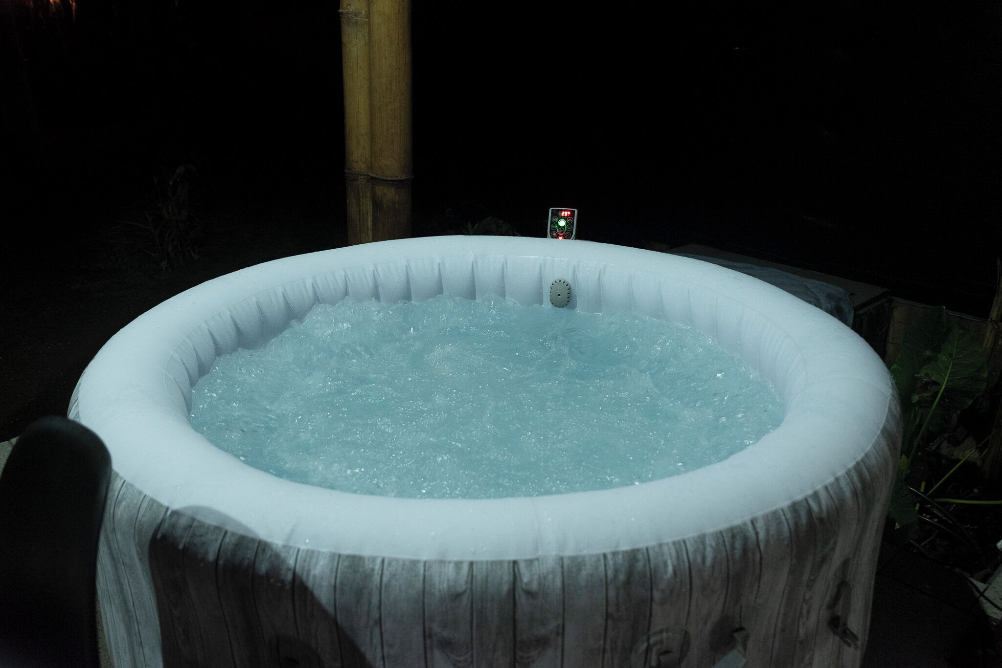 A hot tub with a control panel on top, surrounded by a wooden structure.