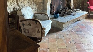 Une pièce rustique avec un mur en pierre, une cheminée, un banc en bois et une chaise rouge.