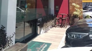 A building with a glass entrance, a red wall, and a signboard. - HOTEL SUITES RESIDENCE (Recife)