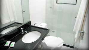 A modern bathroom with a black sink, white toilet, and glass shower enclosure. - HOTEL SUITES RESIDENCE (Recife)