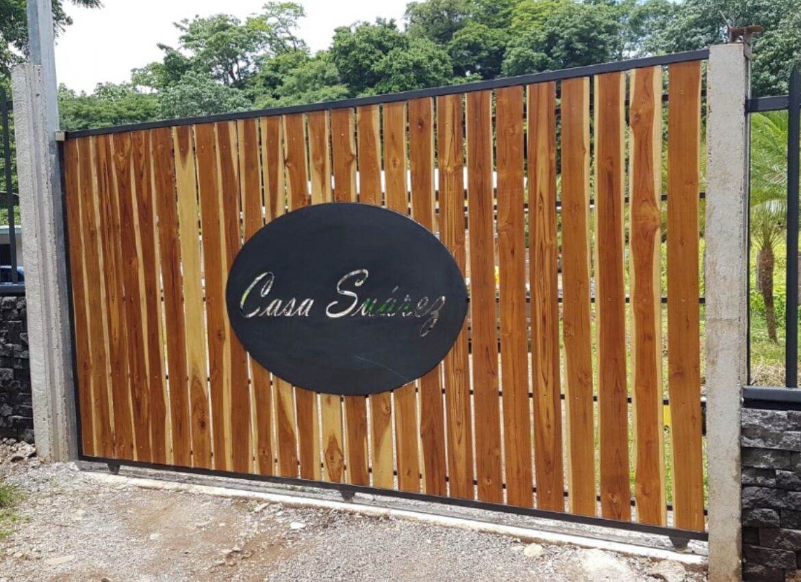 A wooden gate with a circular sign that reads "Casa Suitez".