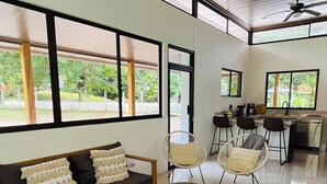 A modern living room with a sofa, chairs, a coffee table, and a kitchen area with a bar. - Cozy modern house with pool and basketball court! (San Fernando de Samara)