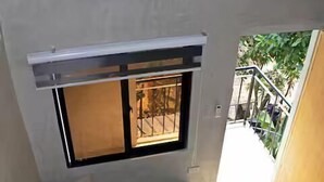 A staircase with a grey bench, a small table with a vase, and a window with a metal grill.