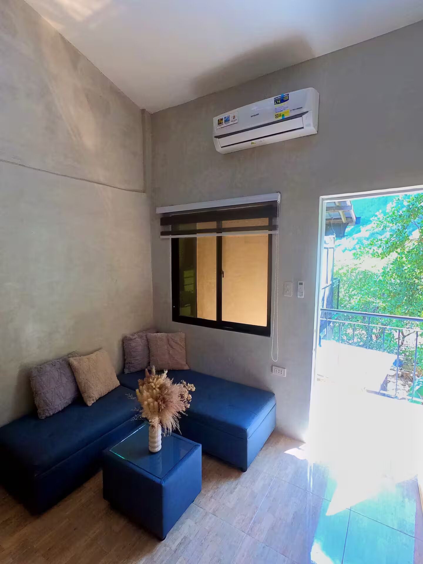 Een moderne woonkamer met een modulaire bank, een kleine salontafel en een groot raam met luxaflex.
