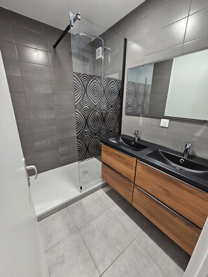 A modern bathroom with a shower, two sinks, and a mirror.