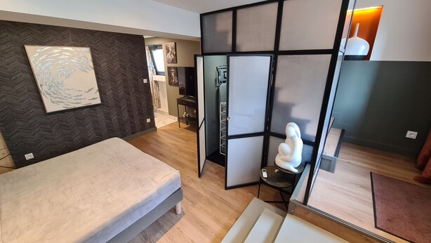 Un dormitorio moderno con una cama, un panel decorativo, una separación con luz y una pequeña estatua.
