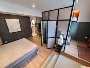A modern bedroom with a bed, a decorative wall, a partition with a light, and a small statue. - Modern duplex with air conditioning, quiet and comfort (Champlay)