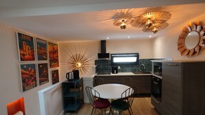Una cocina moderna con una isla central, una mesa de comedor con sillas y un refrigerador.