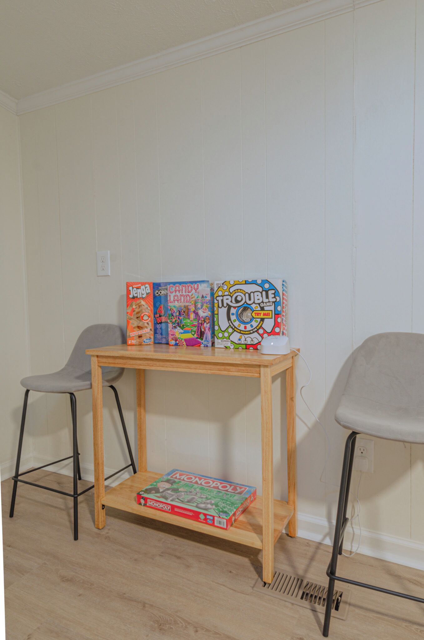 Un tavolo di legno con tre giochi da tavolo: Jenga, Candy Land e Trouble. Un gioco di Monopoly è sul pavimento accanto al tavolo.