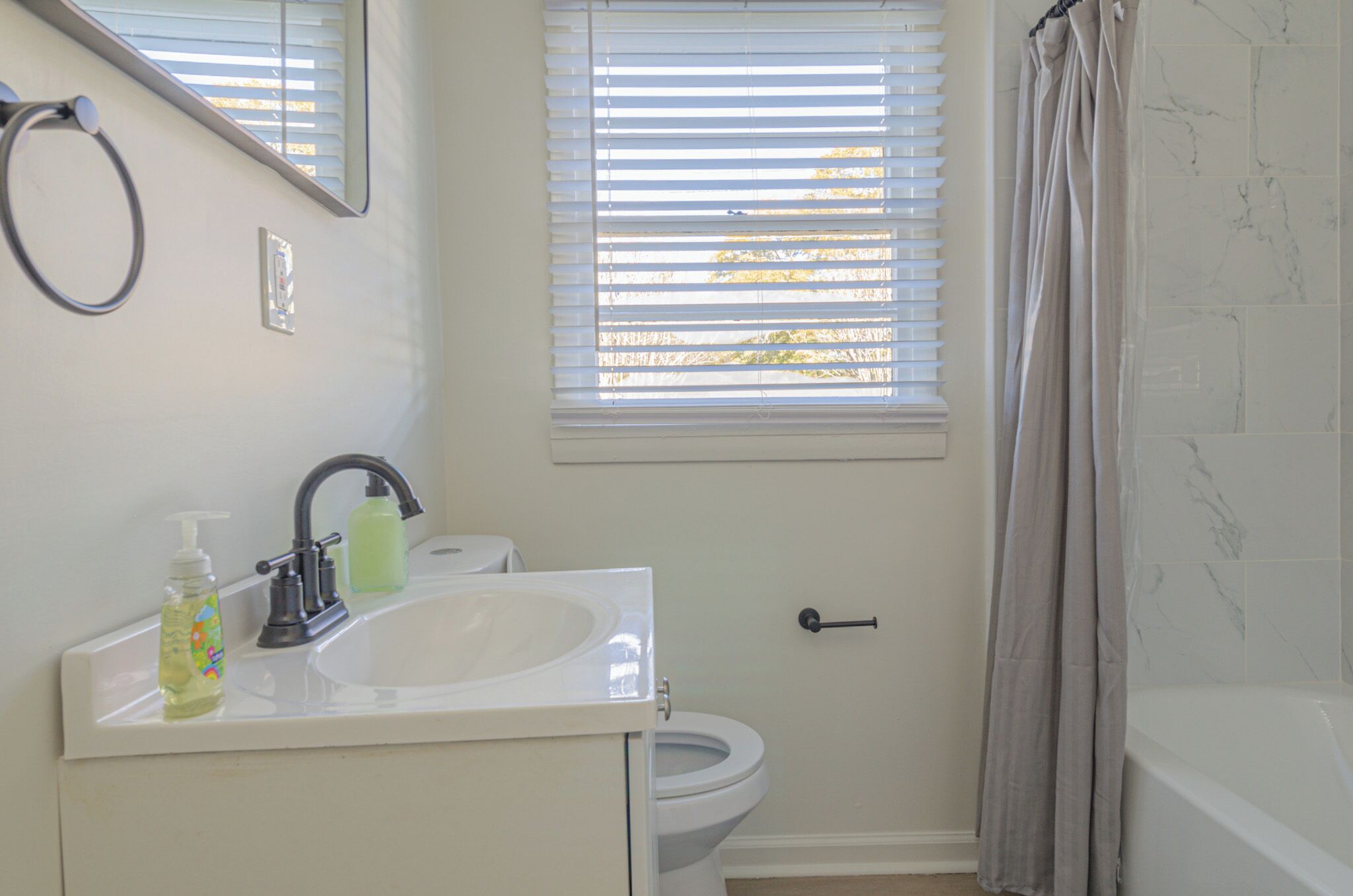 A bathroom with a sink, toilet, and window with blinds.