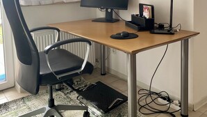 Un petit bureau comprenant un bureau, un ordinateur, une chaise et un radiateur.