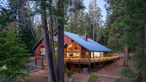 A rustic cabin with a wooden exterior, large windows, and a covered deck.
