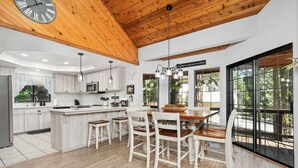 A modern kitchen with wooden ceiling beams, white cabinetry, and a central island with seating.