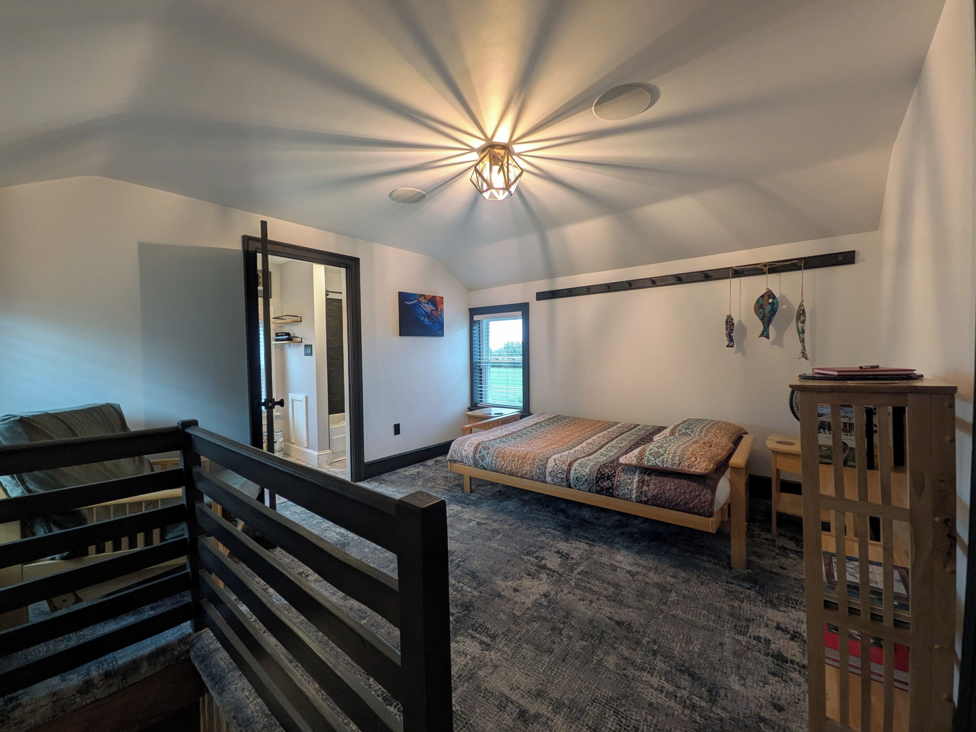 Un dormitorio con cama, escritorio, silla, ventana y puerta que da a un baño.
