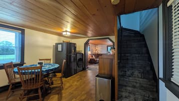 Un interior de madera con comedor, cocina y una escalera que lleva a un nivel superior.
