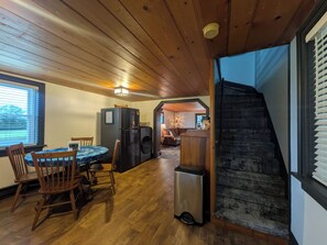 A wooden interior with a dining area, kitchen, and a staircase leading to an upper level.