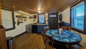 Une cuisine avec des meubles en bois, un lave-vaisselle et une cuisinière. On y trouve une table à manger avec des chaises et une nappe bleue.