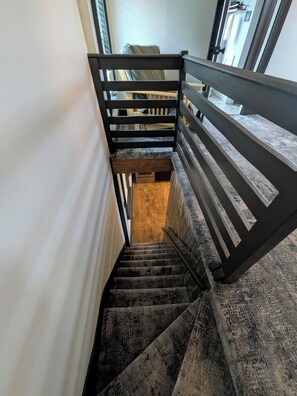 Una escalera con barandilla de madera y peldaños alfombrados que conducen a un rellano.