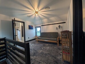 A room with a ceiling fan, a sofa, a wooden cabinet, and a window.