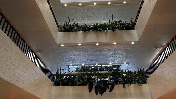 A multi-level atrium with a central skylight, multiple floors, and green plants integrated into the design.