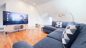 Una sala de estar moderna con un televisor de pantalla plana, un sofá, una mesa de centro y una lámpara.