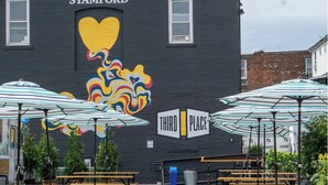 Un edificio con un mural de un corazón y arte abstracto colorido, que dice "STAMFORD THIRD PLACE".