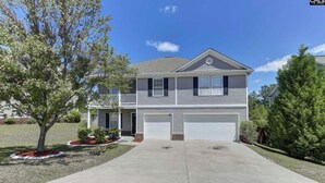 A two-story house with a front garage, a small porch, and a well-maintained lawn.