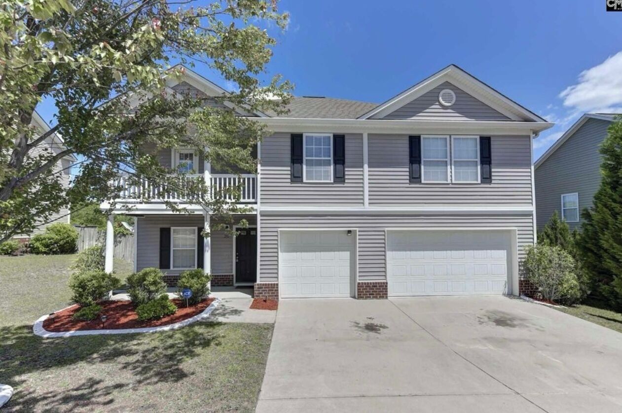 A two-story house with a front garage, a covered porch, and a landscaped front yard.