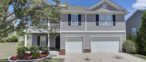 A two-story house with a front garage, a covered porch, and a landscaped front yard.