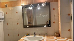 A bathroom with a sink, mirror, and shower.