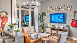 A modern living room with a large TV, a chandelier, and a 'Music City' sign on the wall. - Nashville Skyline View with a Rooftop Deck that Sleeps 12 People (Nashville)