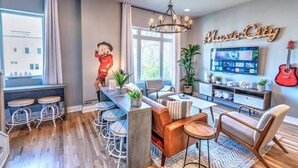 A modern living room with a bar area, a large TV, and a 'Music City' sign. - Nashville Skyline View with a Rooftop Deck that Sleeps 12 People (Nashville)