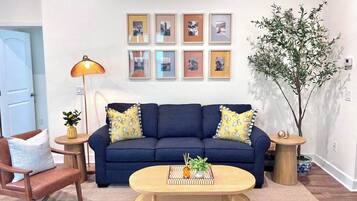A living room with a sofa, two side tables, a coffee table, and a lamp.