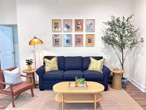 A living room with a sofa, two side tables, a coffee table, and a lamp.